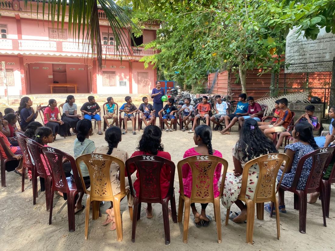Children and mentors gathered in a discussion circle outdoors