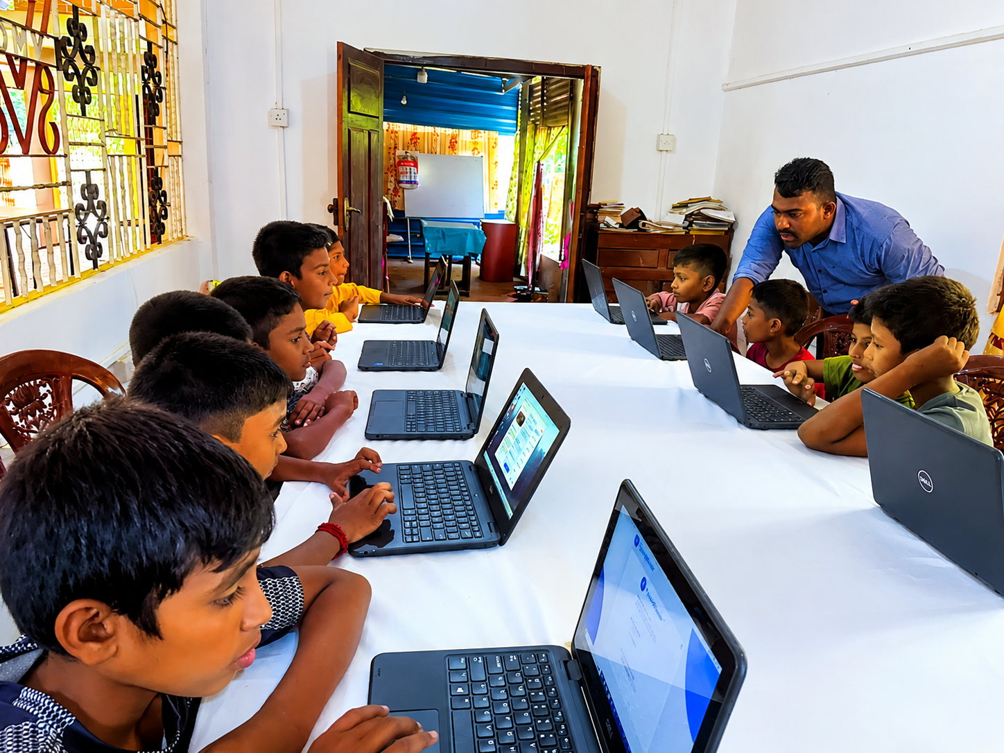 A child smiling while learning computer skills with a CPYE instructor